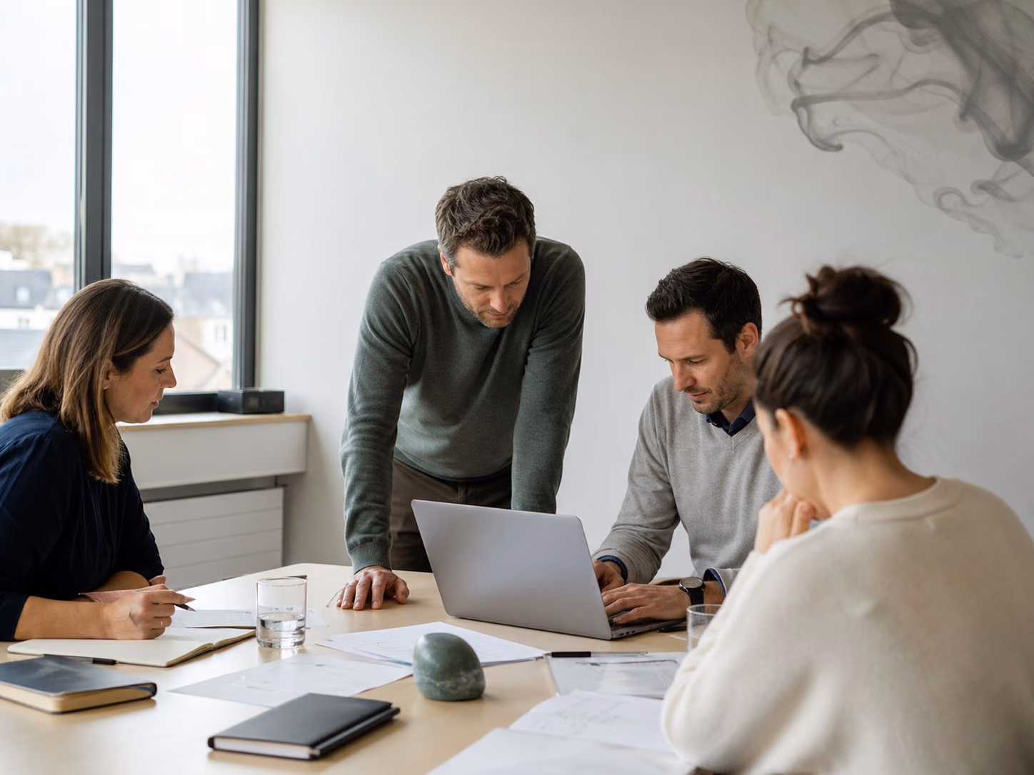 A team works around a table reviewing documents and a computer